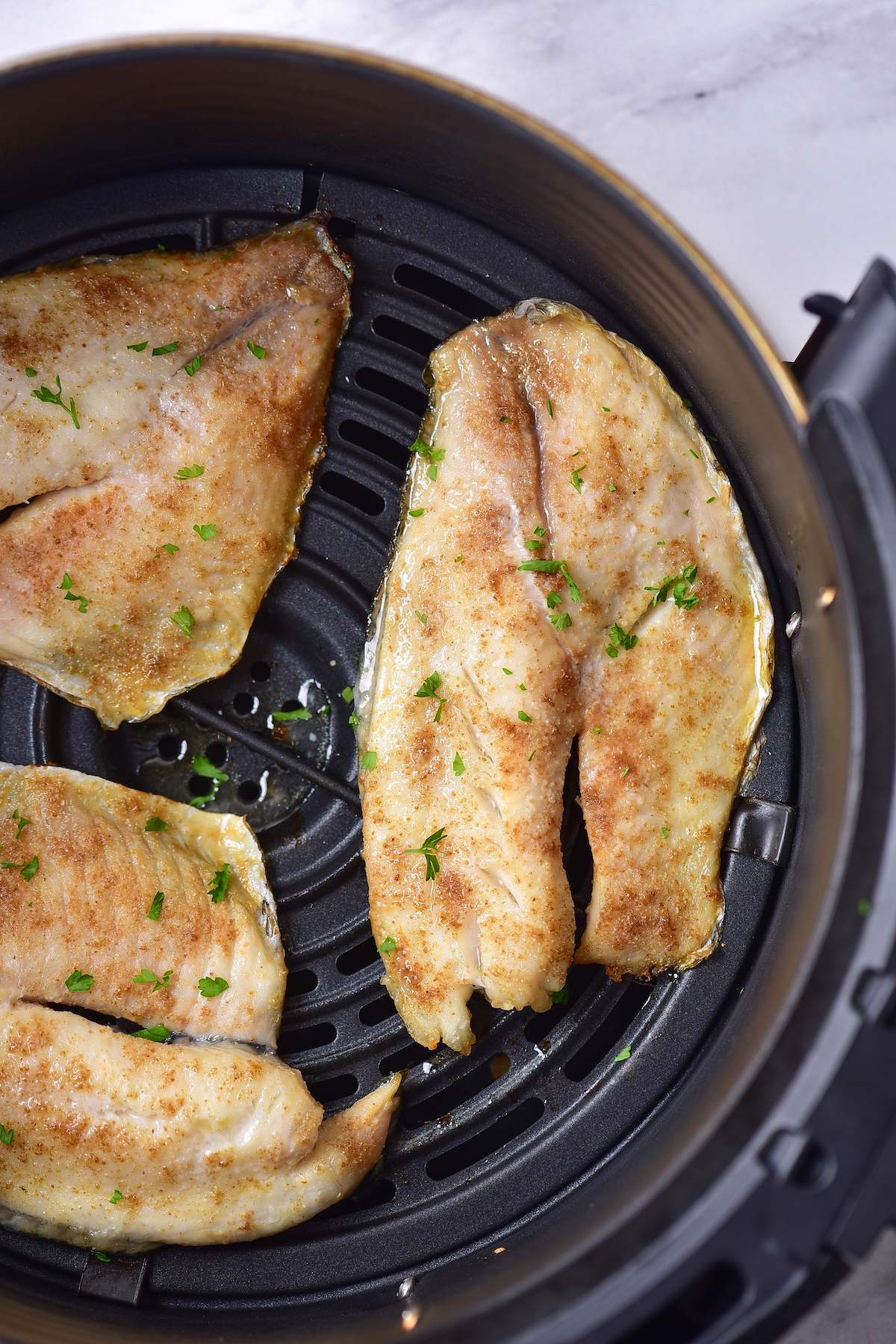 top down view of the finished air fryer tilapia in the air fryer basket