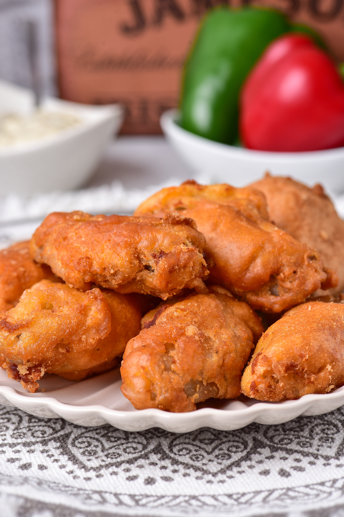 side view of a plate filled with deep fried chicken wings set in front of a dish of dipping sauce