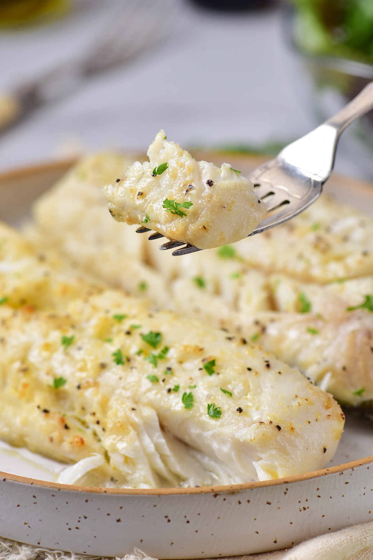 a fork removing one bite of air fryer cod from a plate