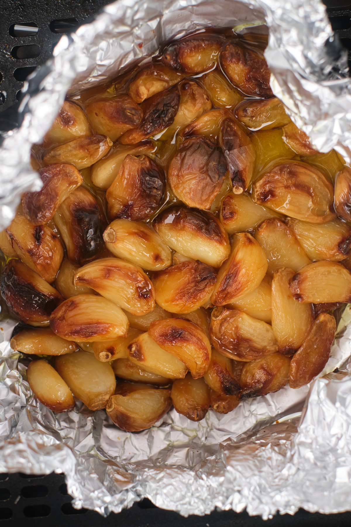 close up of the completed cloves of roasted garlic in air fryer wrapped in foil