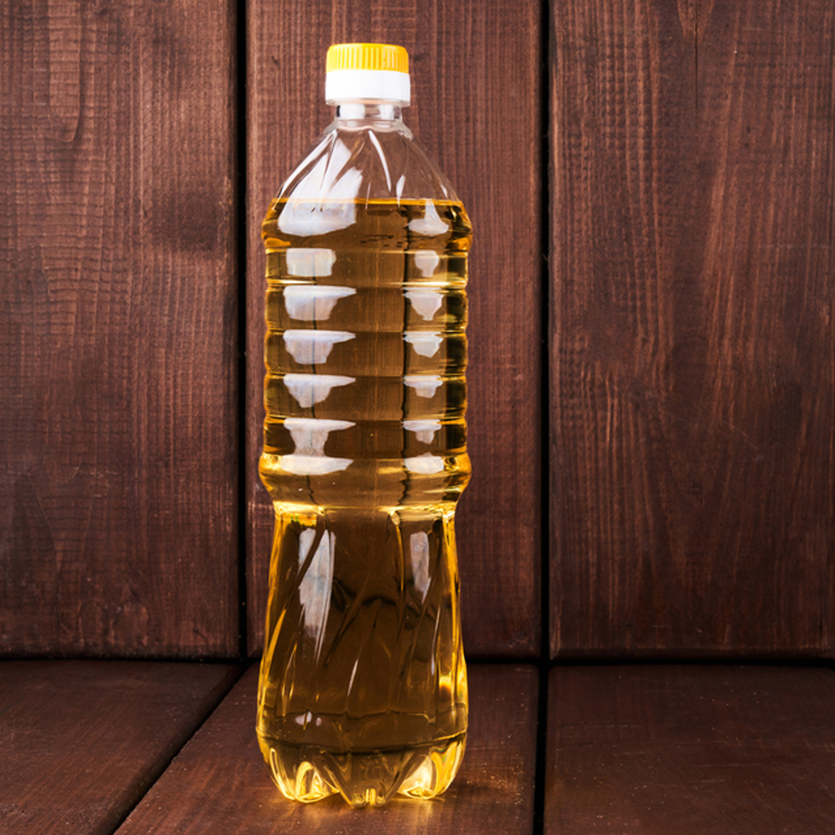 A plastic bottle of vegetable oil against a dark wood background.