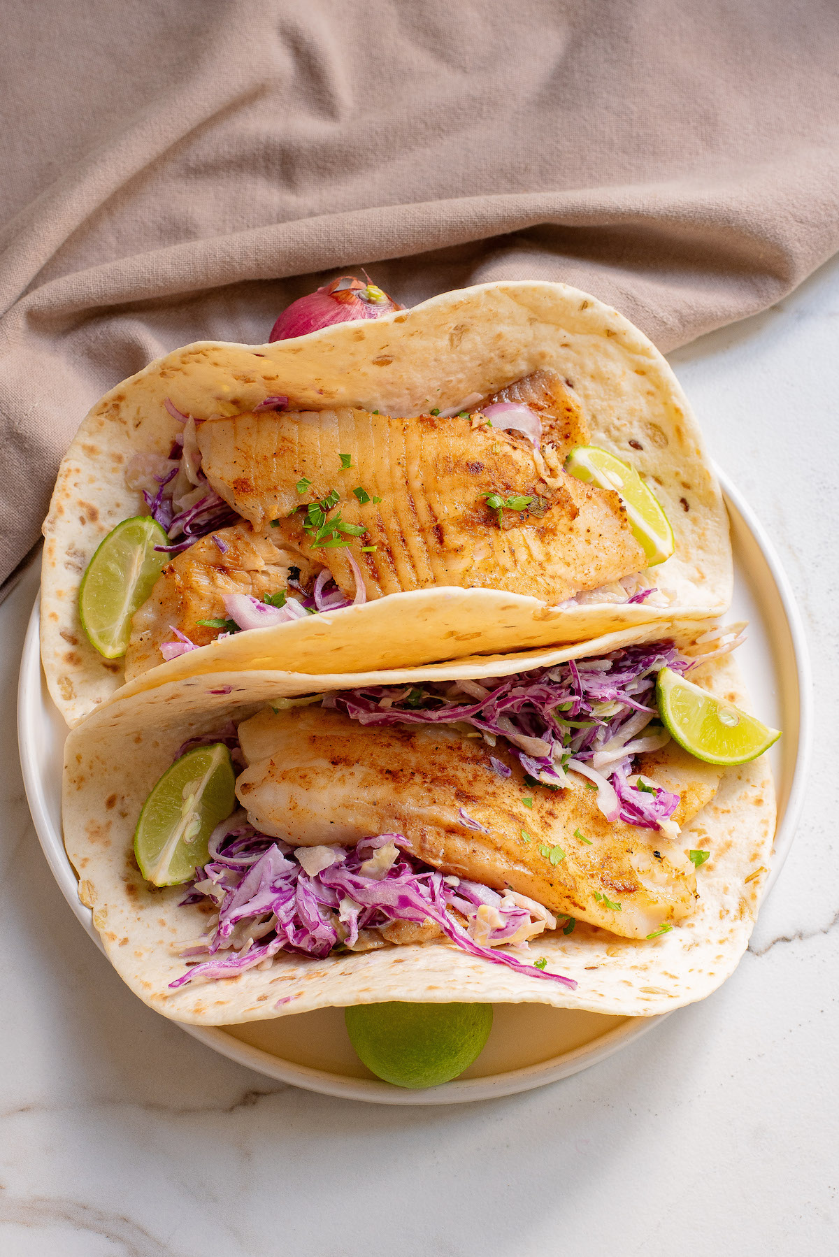 close up view of two completed air fryer fish tacos served on a plate