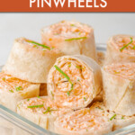 A stack of buffalo chicken pinwheels in a glass dish