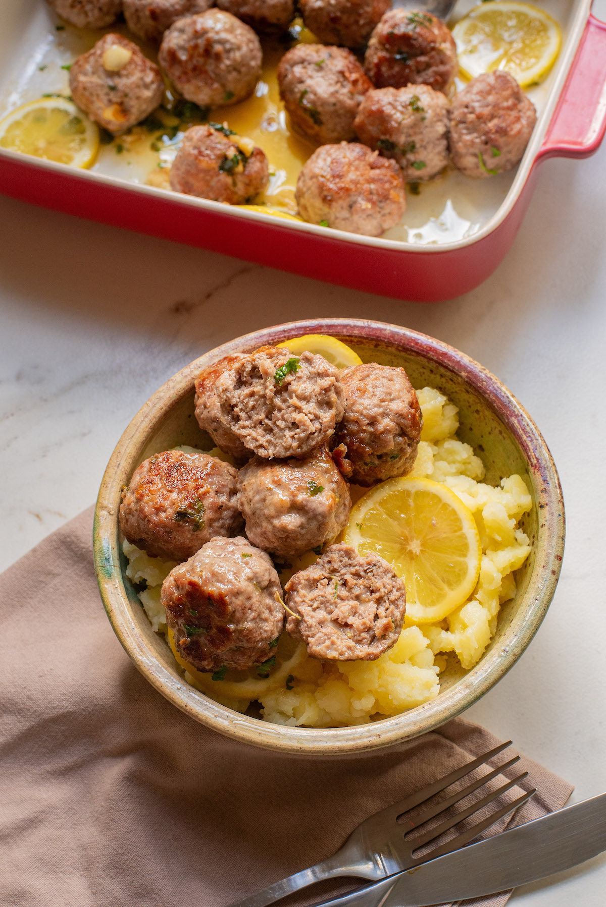 one bowl filled with baked turkey meatballs sitting next to the baking dish