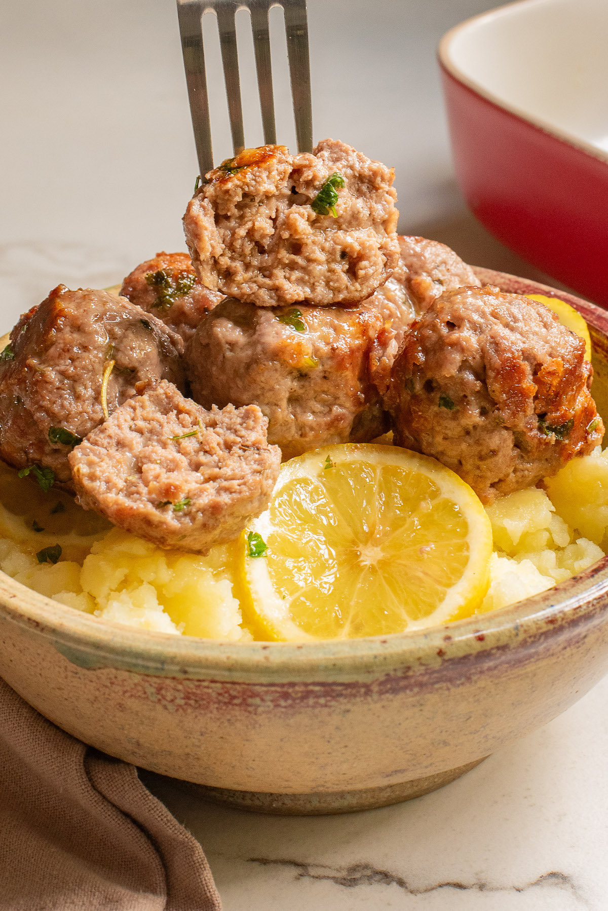 a bowl of baked turkey meatballs with a fork removing one