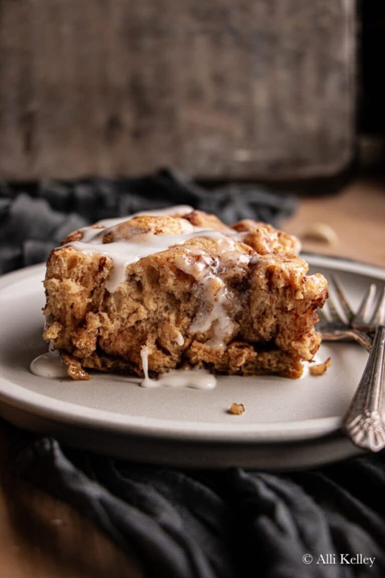 A slice of Crock Pot Cinnamon Roll Casserole on a white plate with forks.