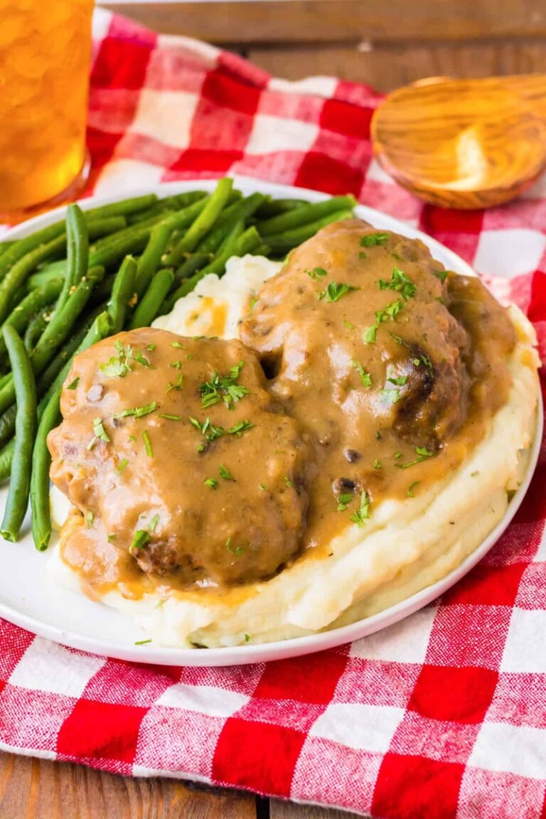  Slow Cooker Salisbury Steaks on a white plate with mash and beans.