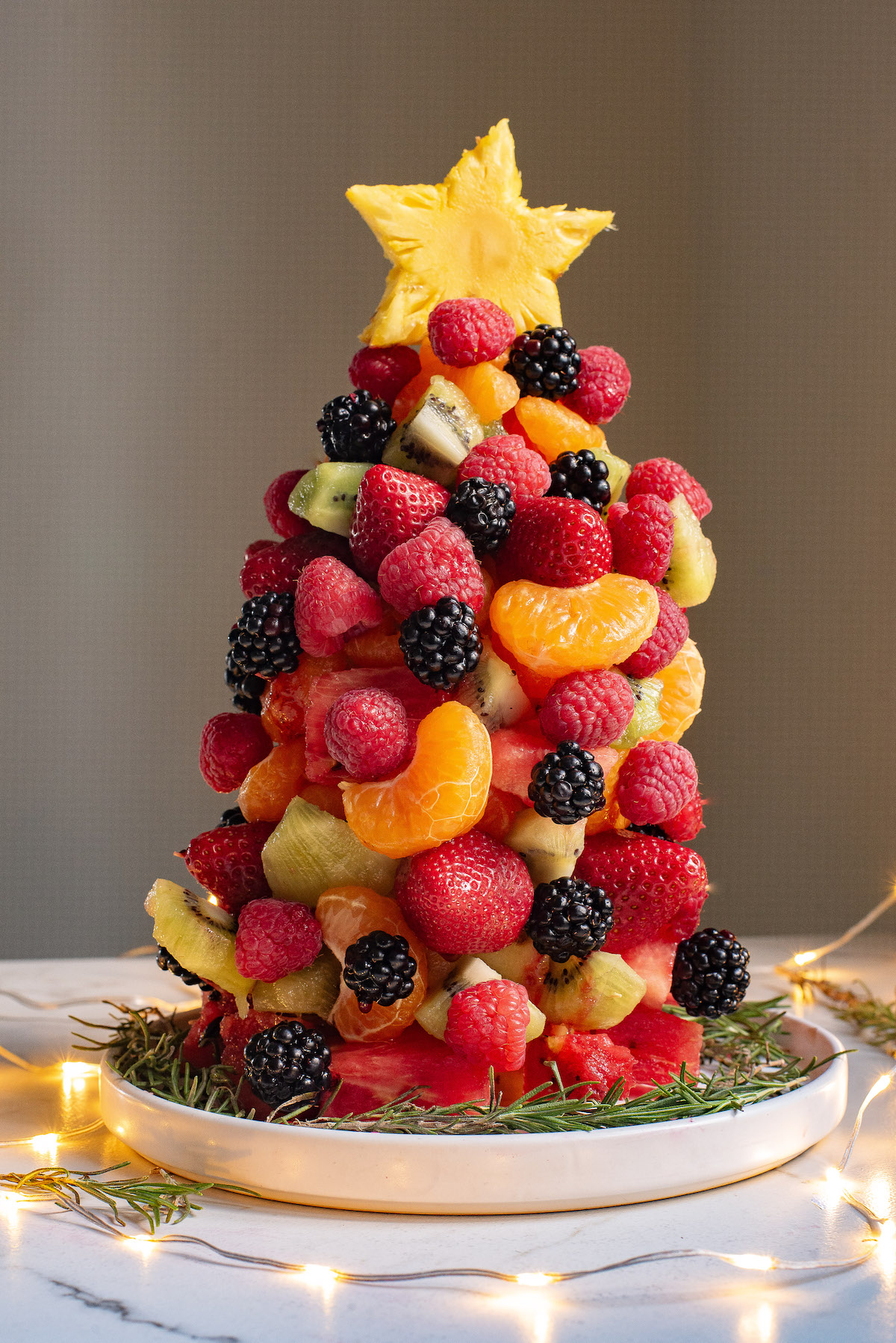 the completed fruit christmas tree on a serving platter and surrounded by lights