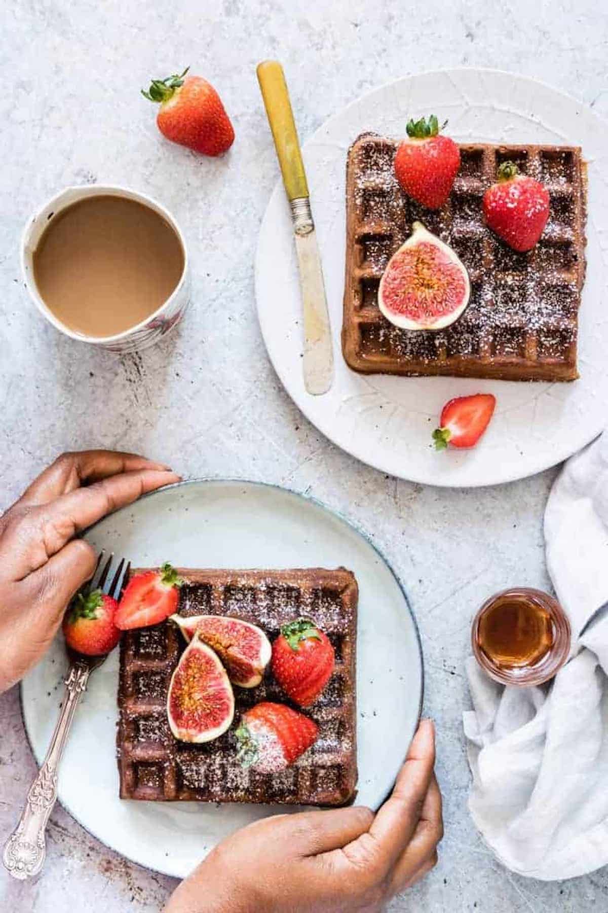 two hands around a plate of gingerbread waffles