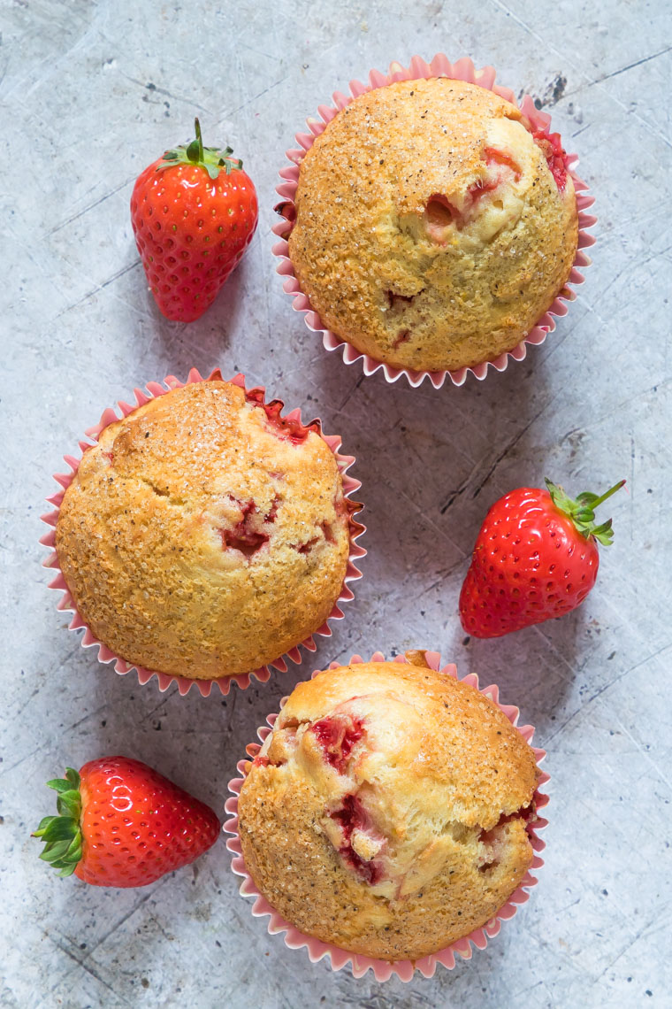 three muffins alongside fresh strawberries