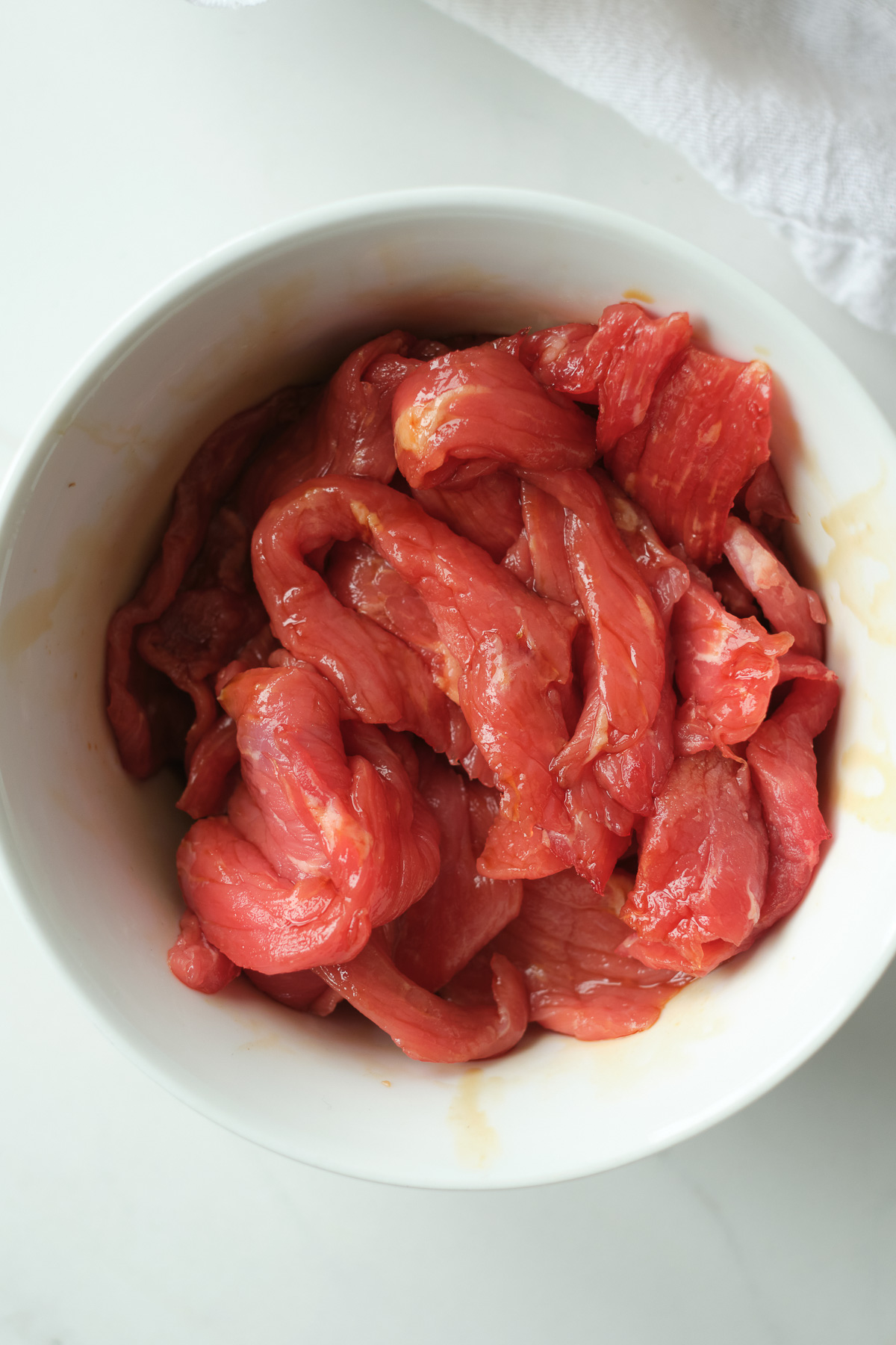 Top down view of raw Beef in a white bowl.