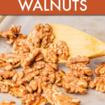 toasted walnuts scattered on a pan with a wooden spoon scooping them up