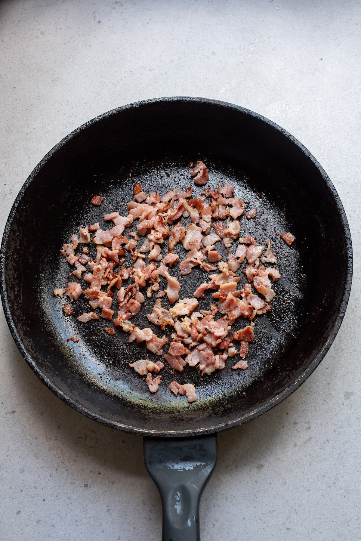 top down view of chopped bacon cooking in a skillet