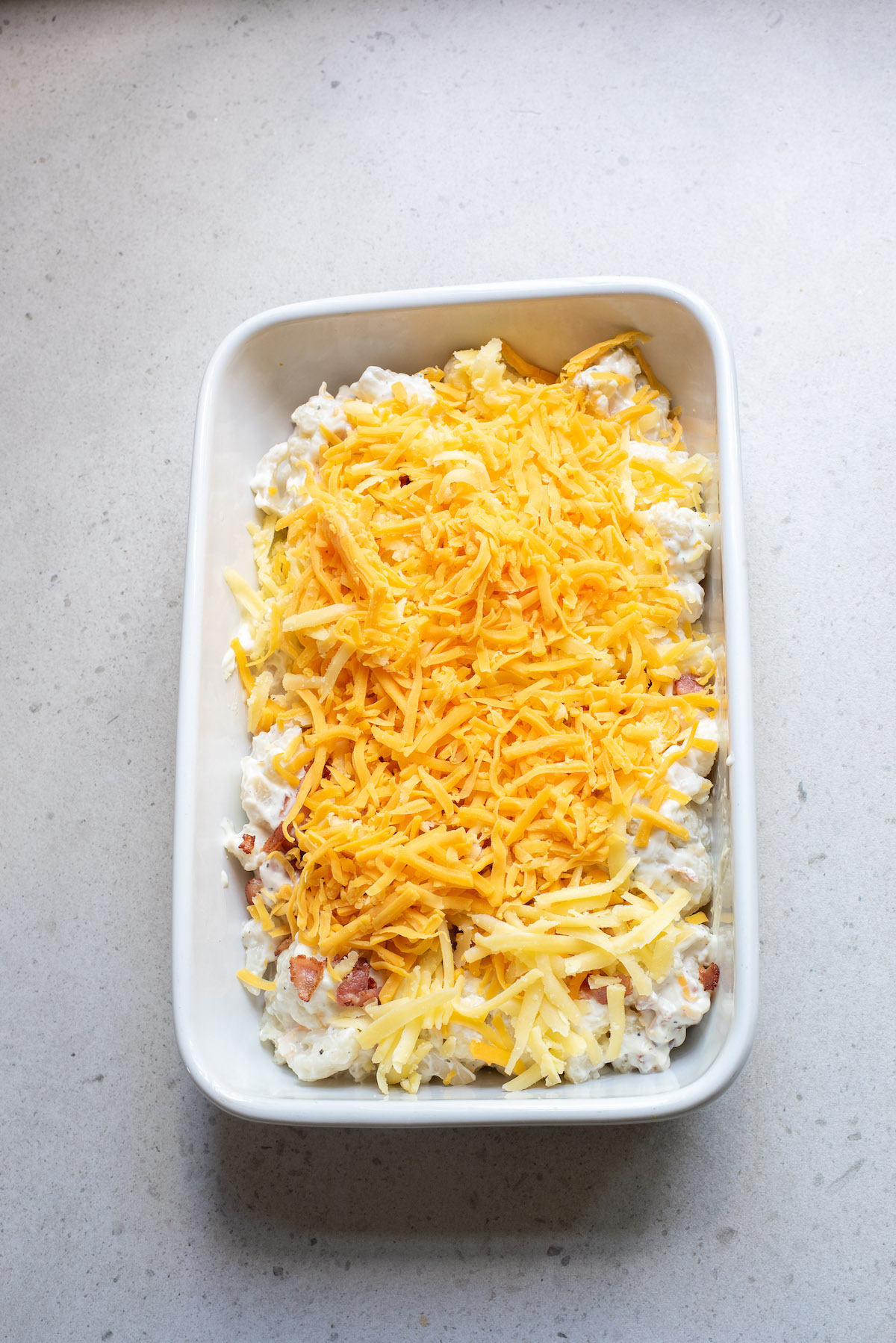 the unbaked casserole topped with shredded cheese