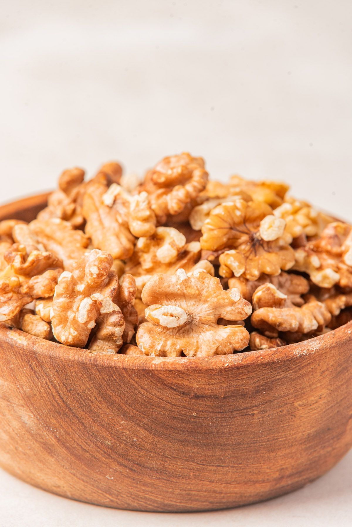 a wooden bowl filled with toasted walnuts
