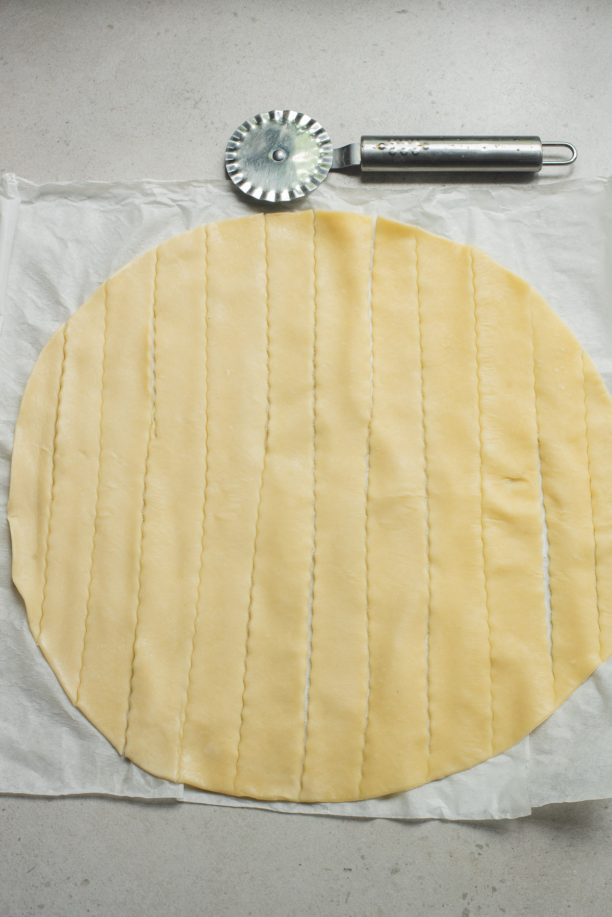 one pie crust being cut into 2-inch strips