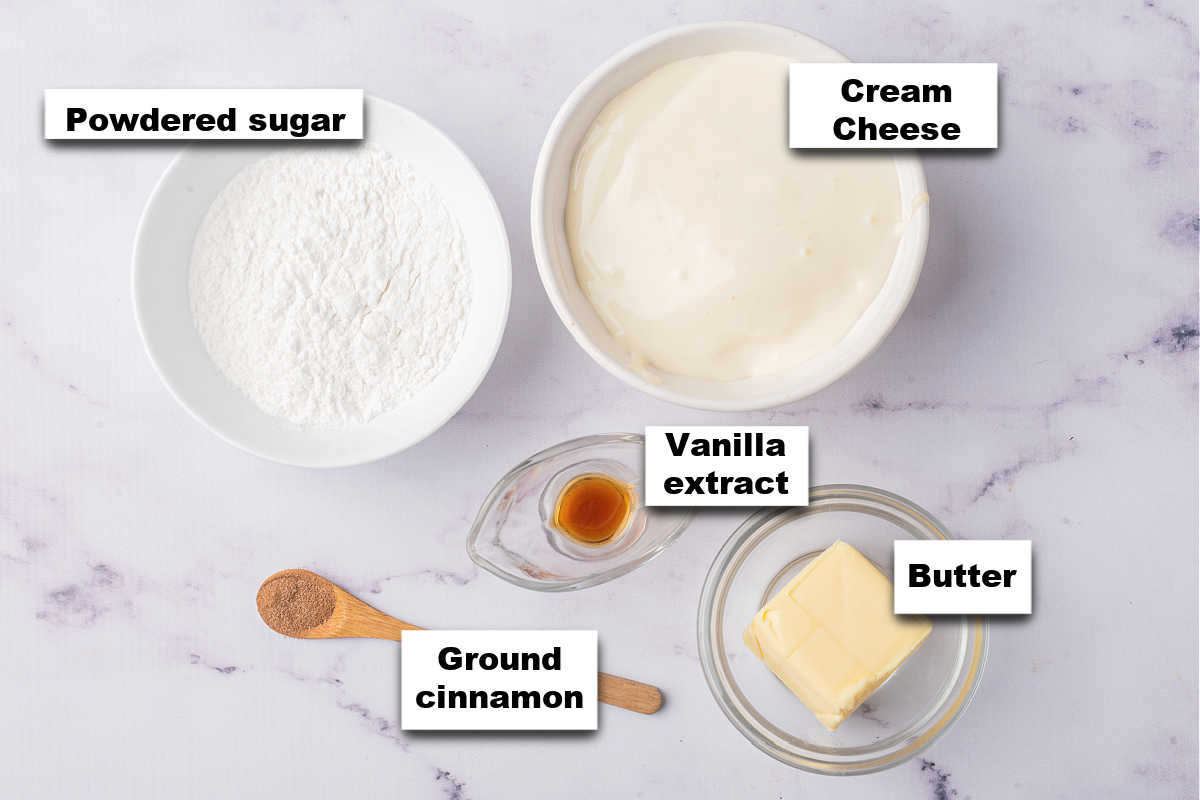 Ingredients for a pumpkin roll icing laid out on a marble surface.