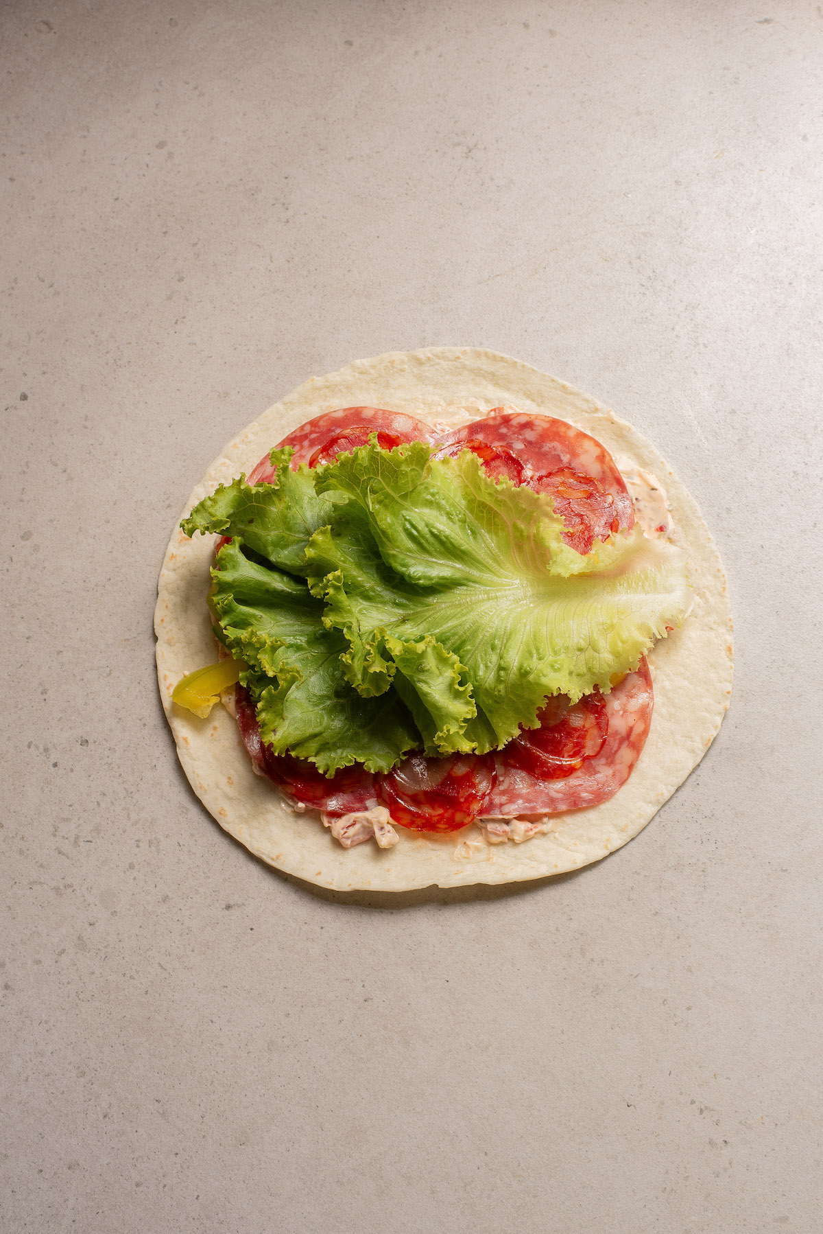 one flat tortilla with the sandwich ingredients on top