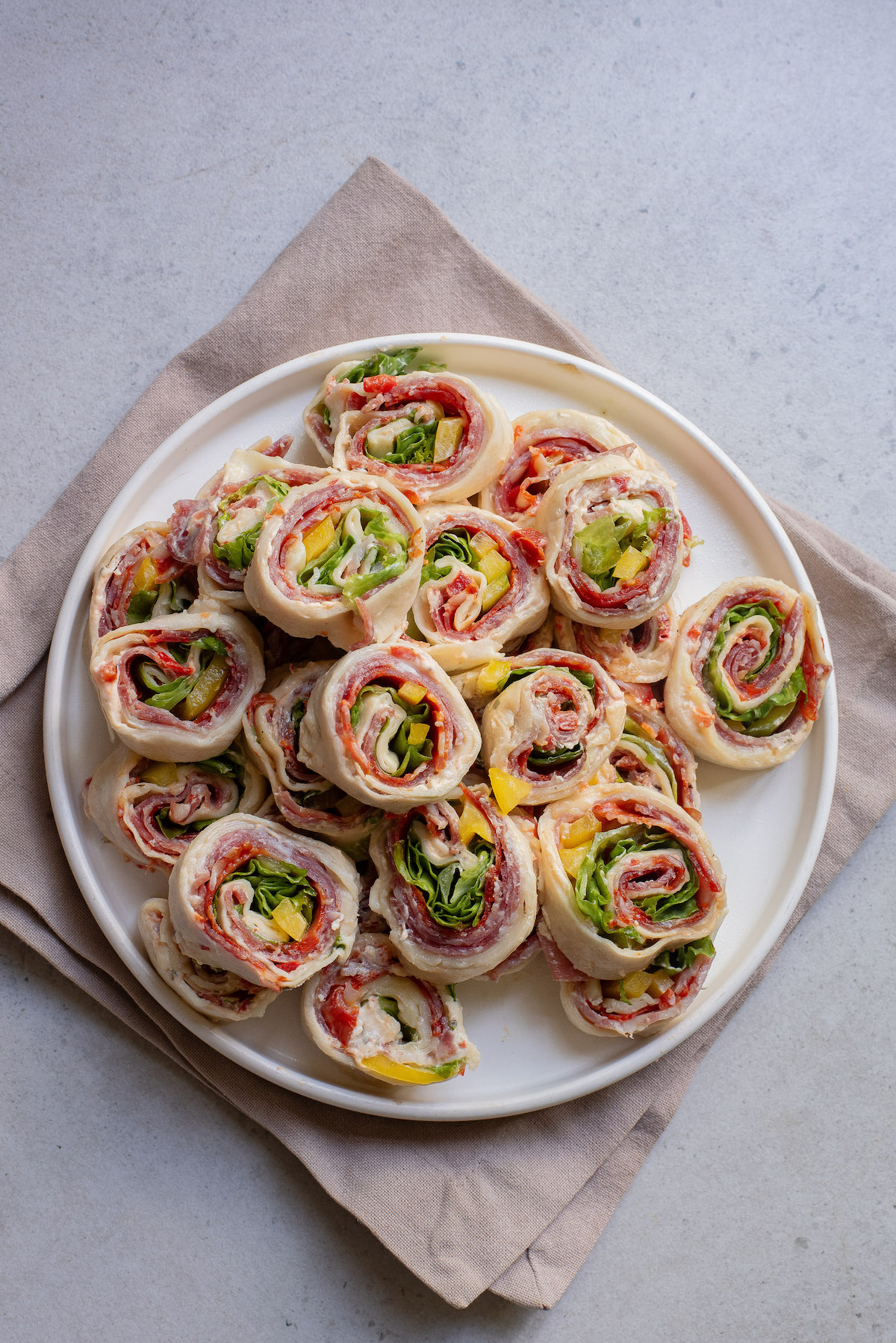the completed Italian sandwich roll ups stacked on a white serving platter