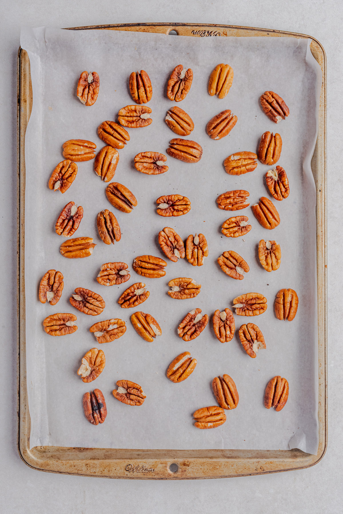 top down view of pecan halves on parchment paper lined baking sheet