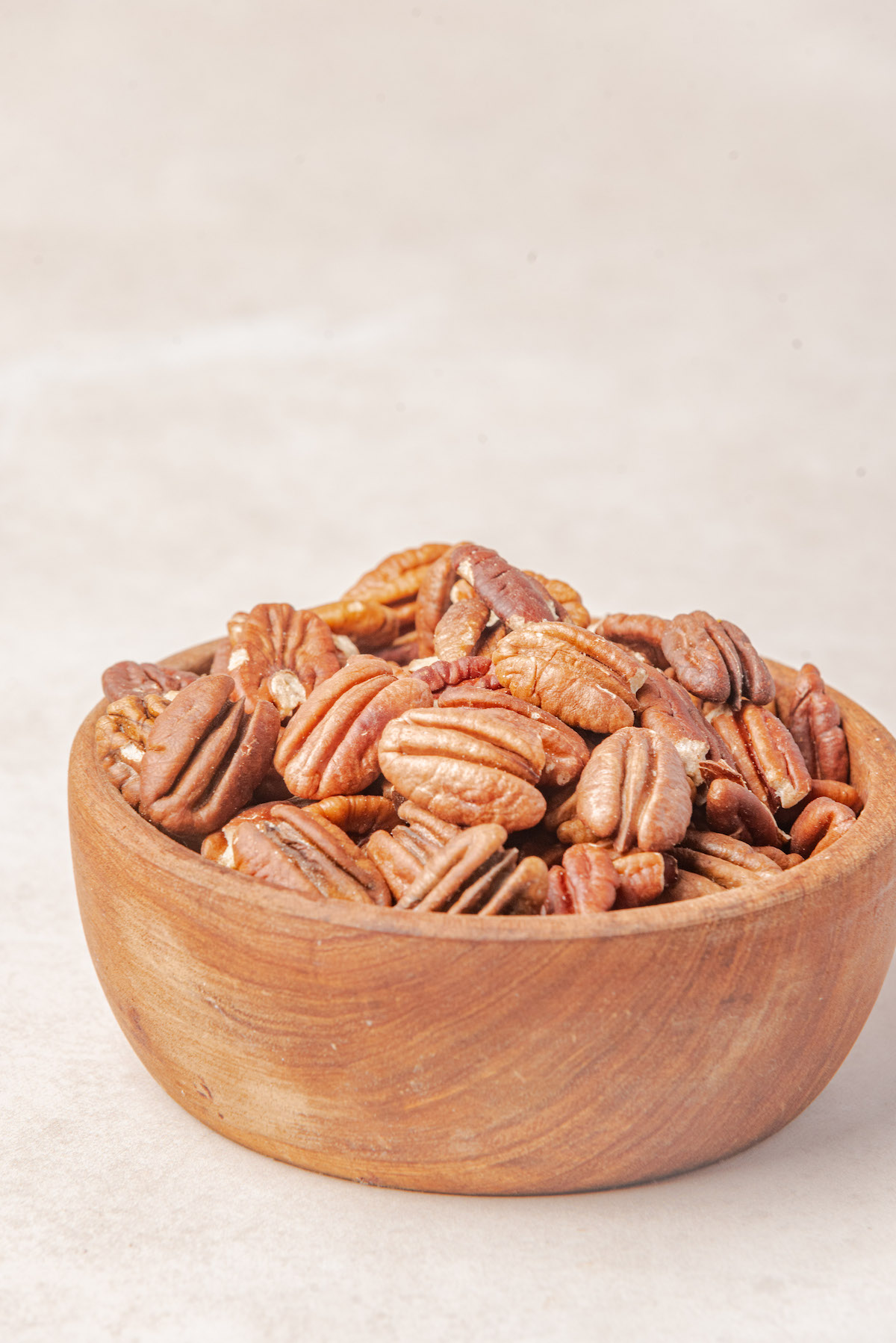 a wooden bowl containing the finished toasted pecans