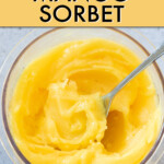 A spoon scooping mango sorbet out of a jar
