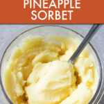 a spoon scooping pineapple sorbet out of a jar.