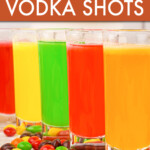 A row of multicolored skittles vodka shots with skittles scattered around them.