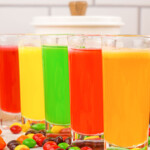 a row of all 5 colors of Skittles shots in glasses