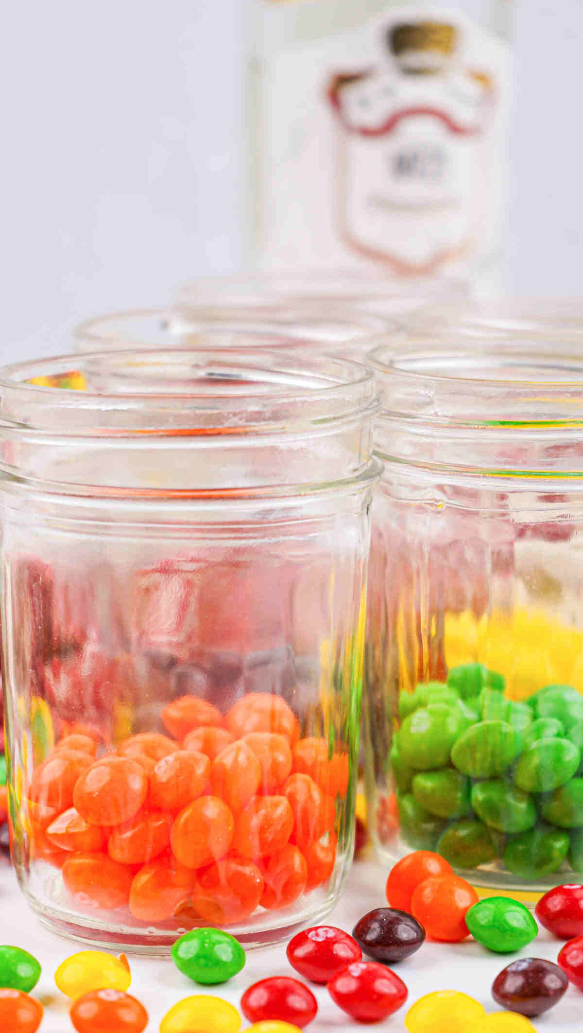 Skittles candy sorted by color and placed in glass jars