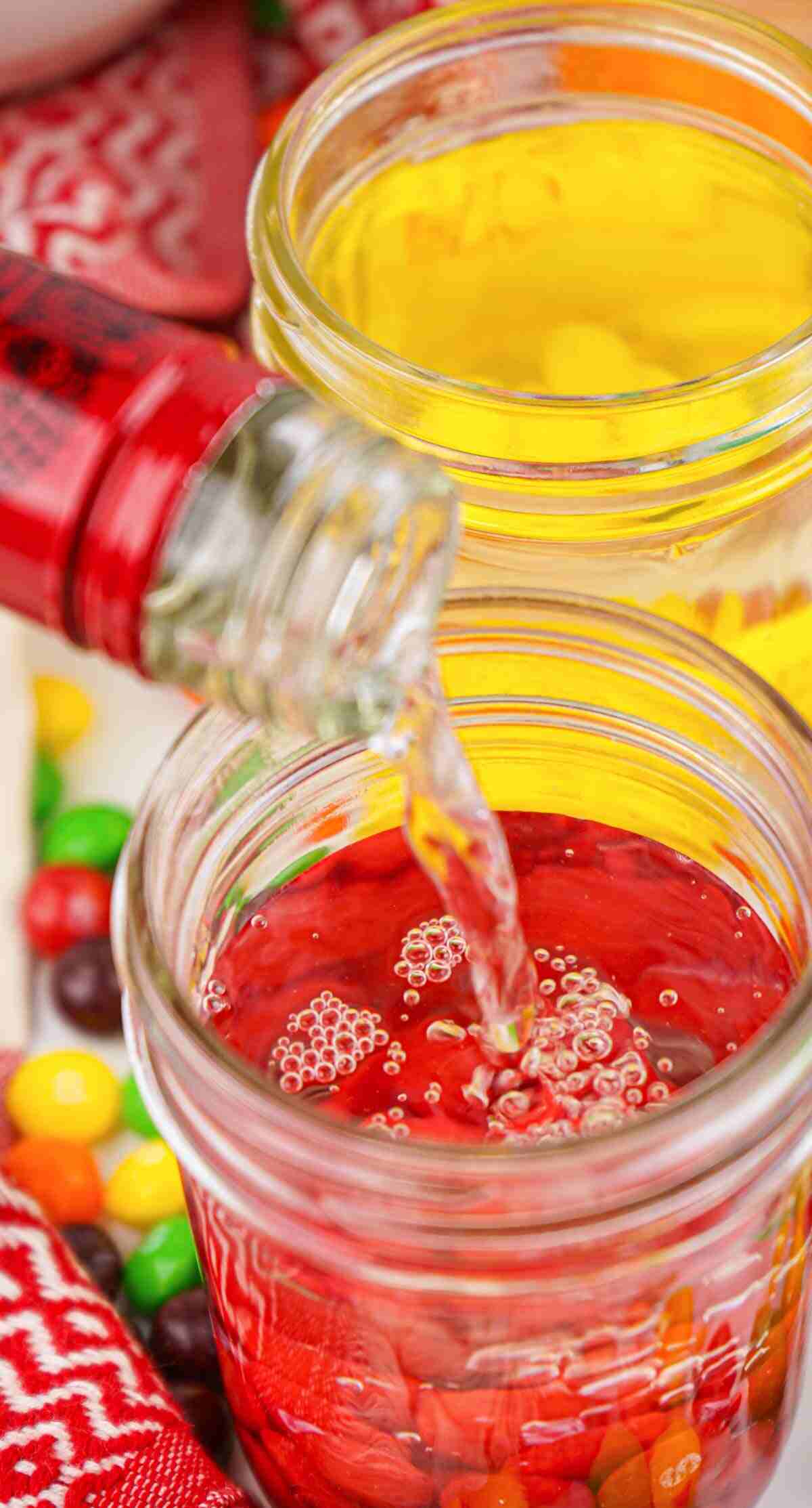 close up view of vodka being added to the jar with the red Skittles