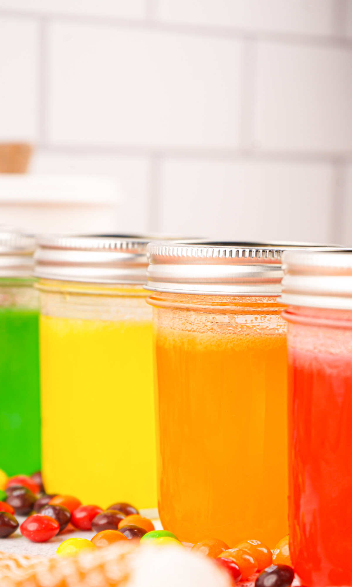 four jars filled with colorful skittles vodka