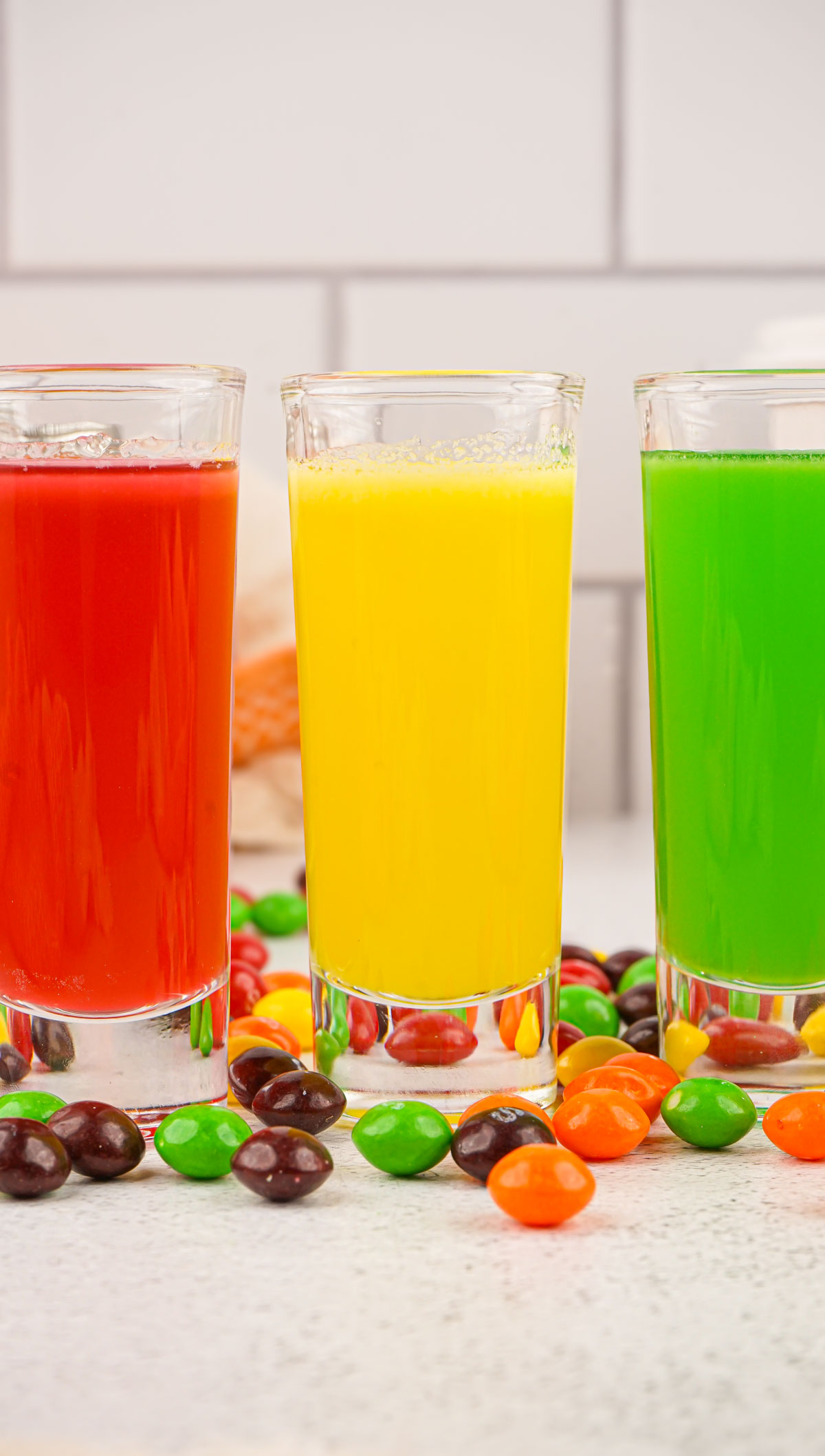 three glasses filled with different colors of the finished skittles vodka