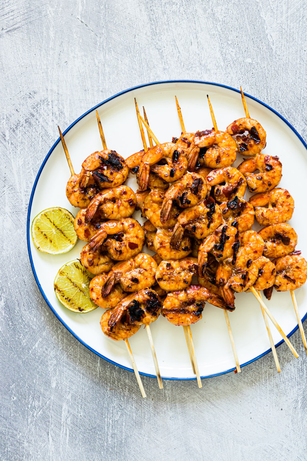 the completed grilled prawns skewers served on a plate with lime wedges