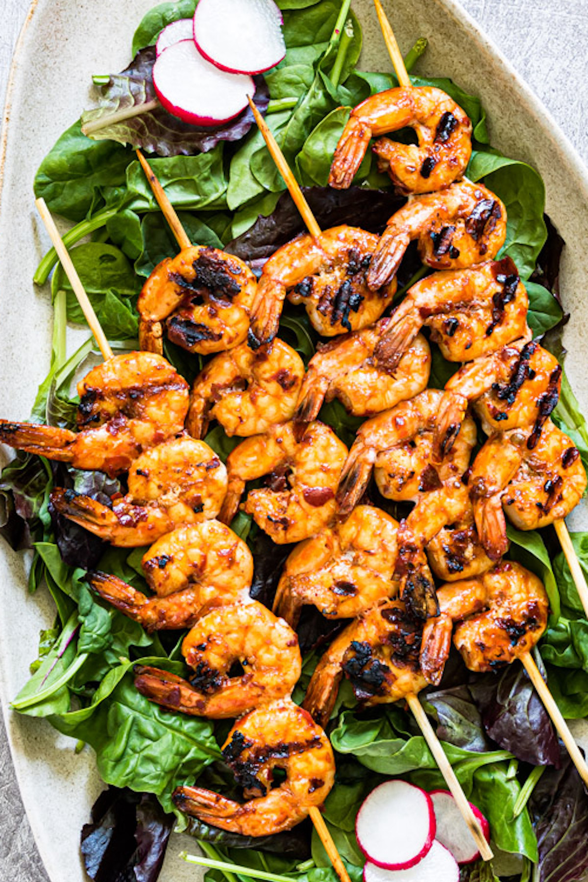 the finished prawns served on the skewers sitting on a beg of lettuce