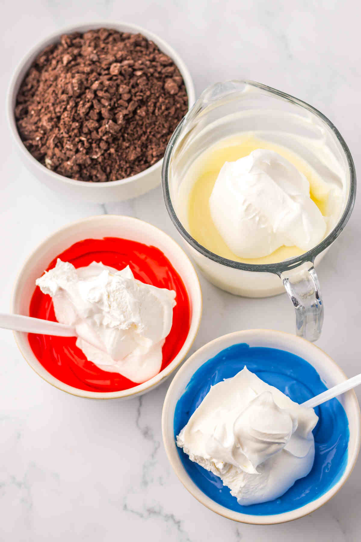 whipped topping being added to the three bowls of colored pudding mixes.