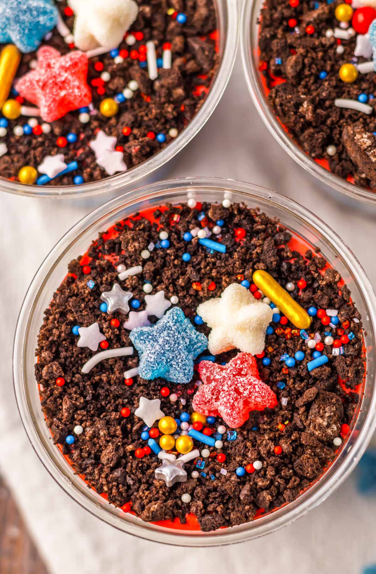 close up view of the top of dirt cup dessert decorated with sprinkles and gummy stars.
