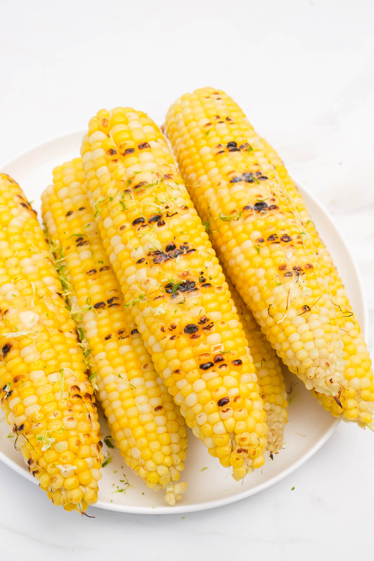 four ears of cooked corn on a plate.