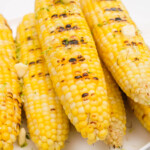a stack of grilled corn on the cob topped with butter