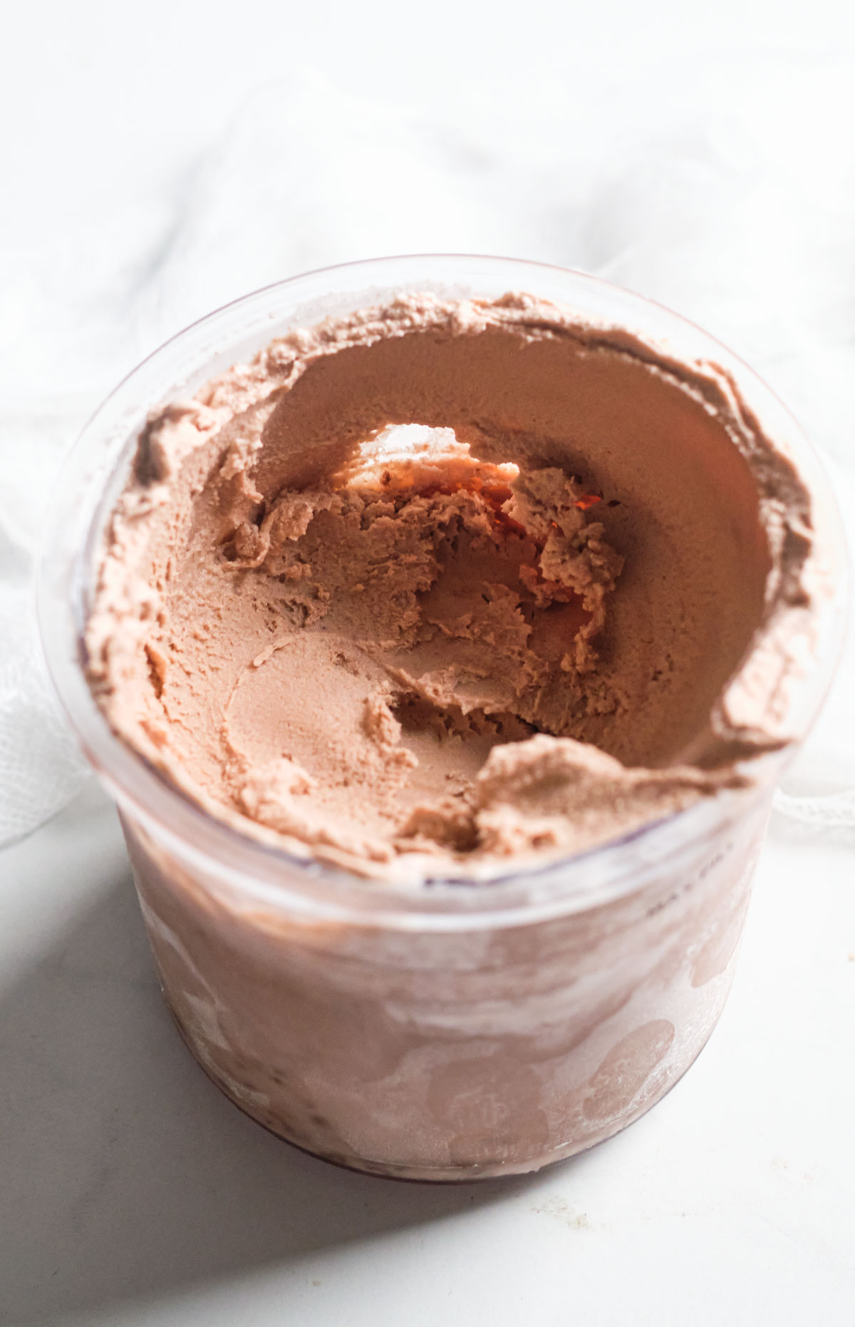 a glass container filled with chocolate ice cream ready to be served.