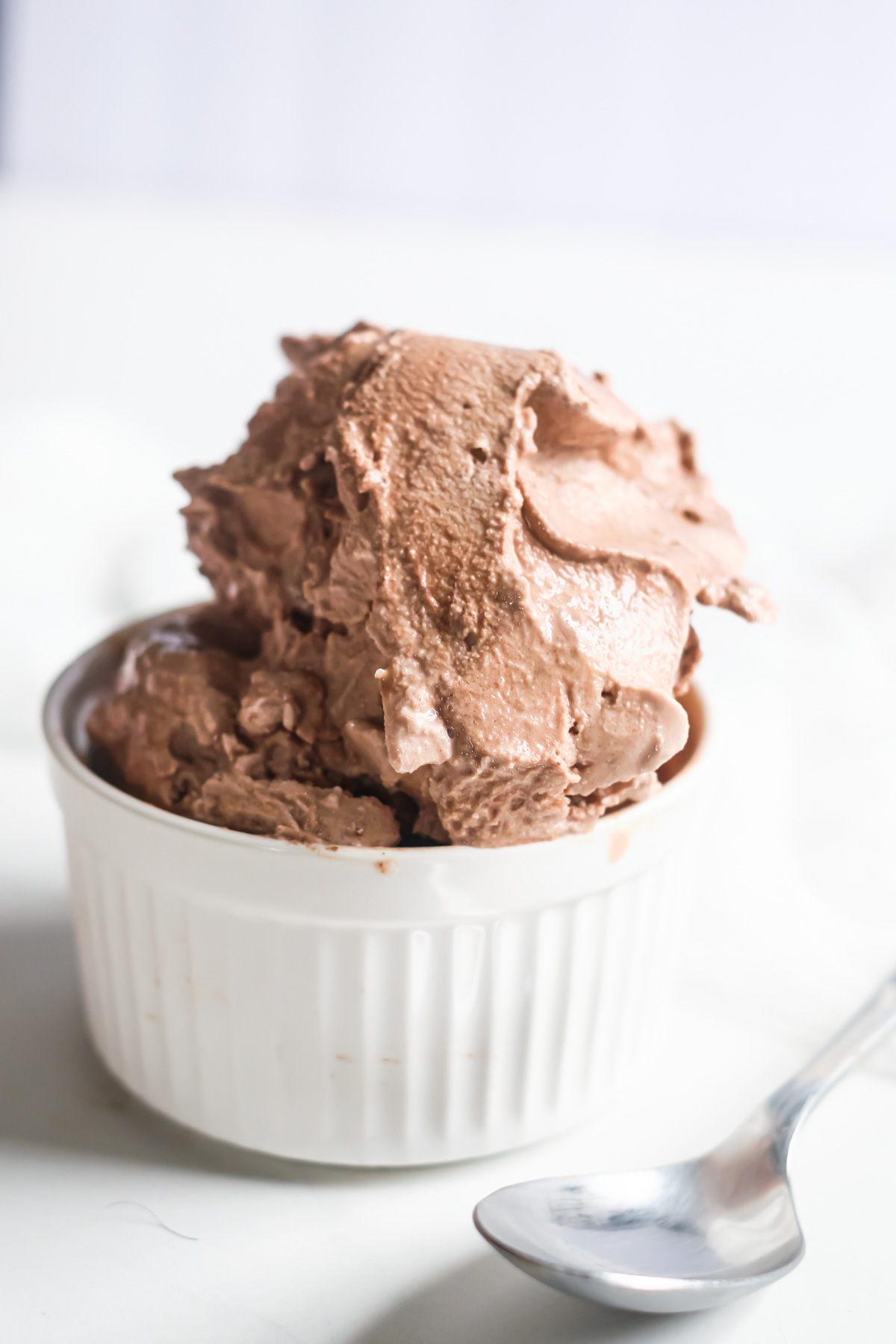 a dessert dish filled with chocolate ice cream and a spoon set in front.