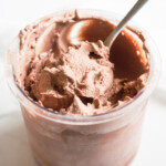 a spoon inside a glass container filled with chocolate ice cream.
