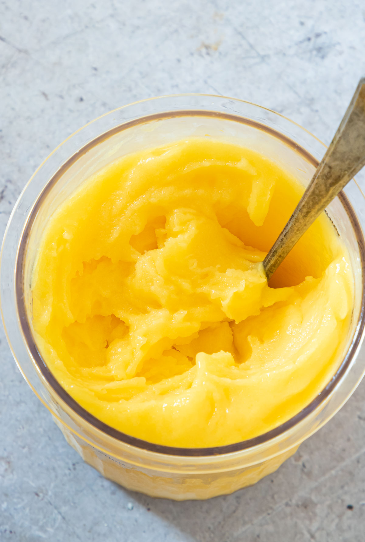 top down view of the processed mango sorbet with a serving spoon inside.