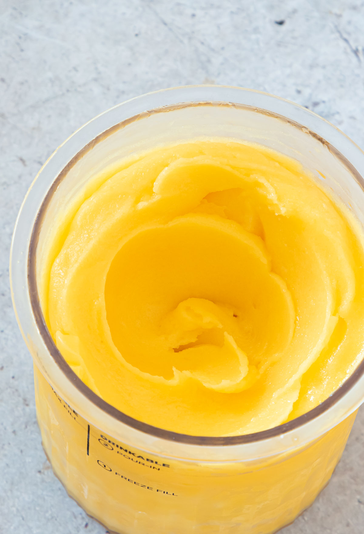 the finished mango sorbet inside the Ninja Creami pint container.