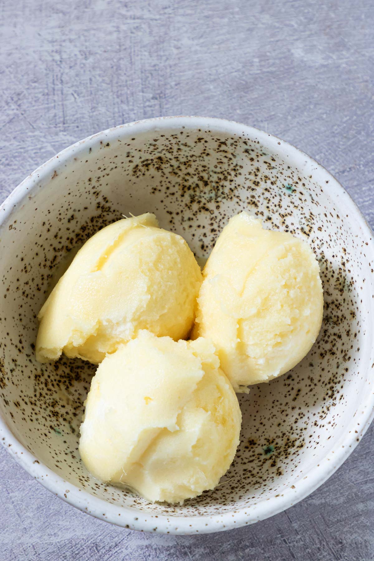 a bowl filled with three scoops of pineapple sorbet.