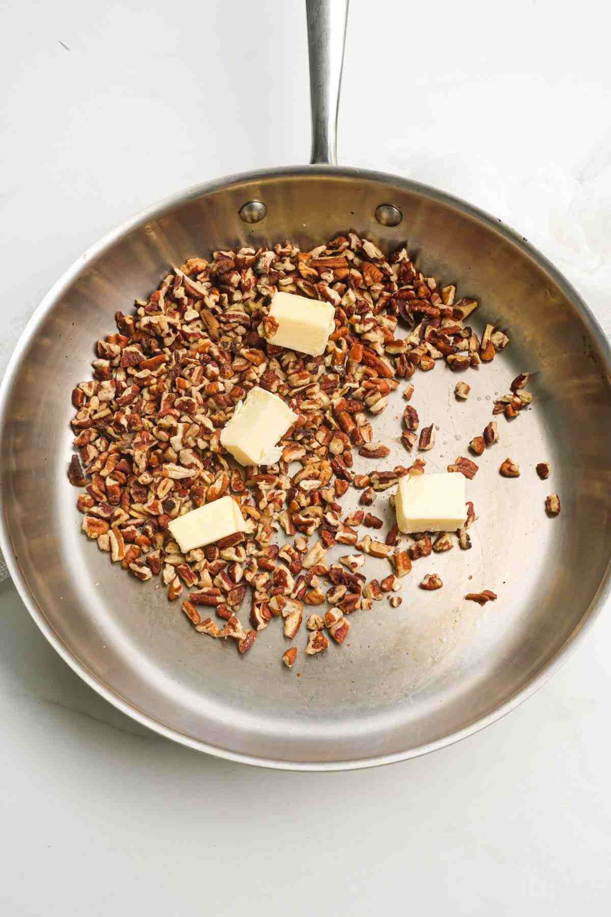 pecans and butter being toasted in a skillet.
