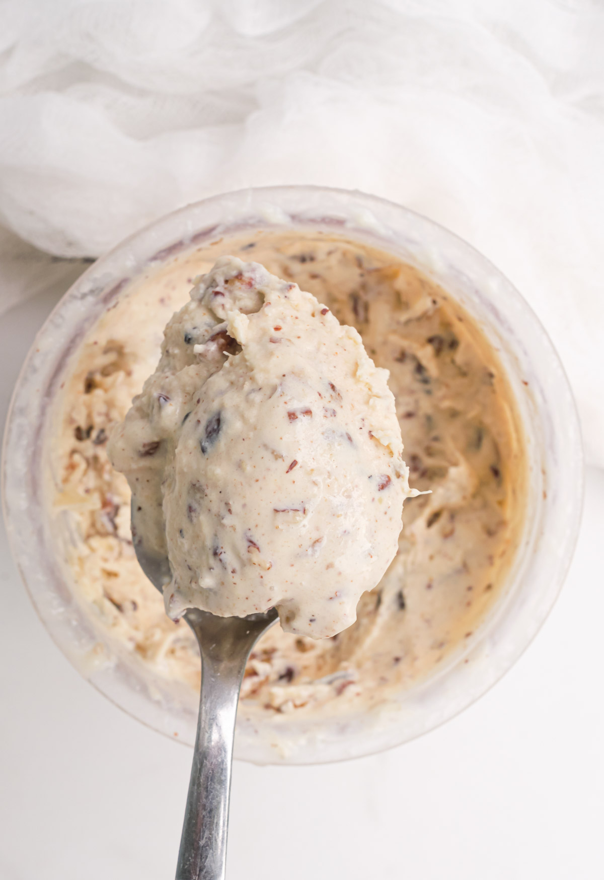 a spoon removing a portion of Ninja Creami butter pecan ice cream from a pint.