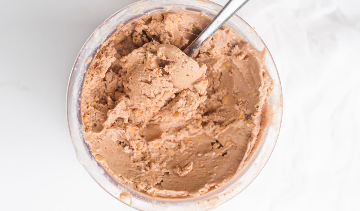 close up view of a spoon dipped inside the chocolate protein ice cream.
