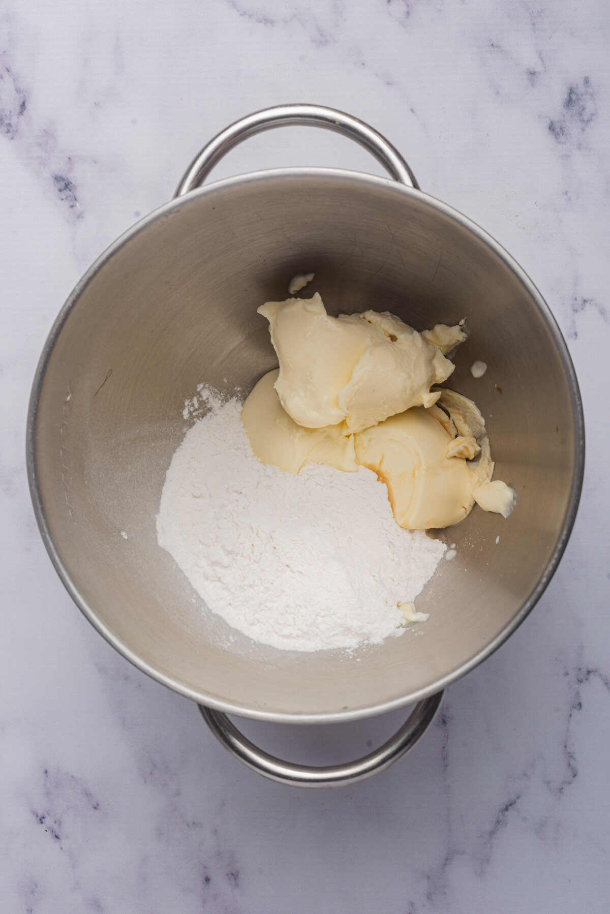 cream cheese, powdered sugar and vanilla inside a mixing bowl.