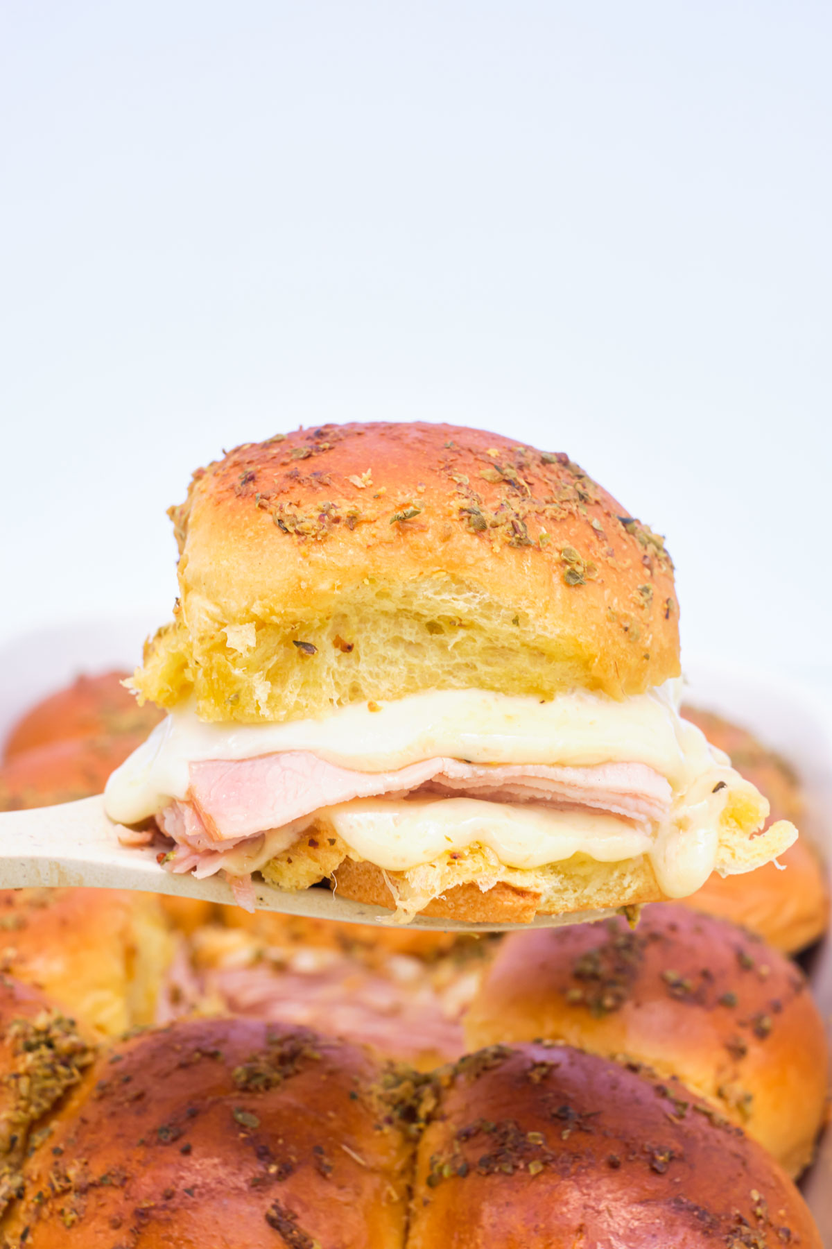 a slider being removed from the baking dish wirth a serving spoon.